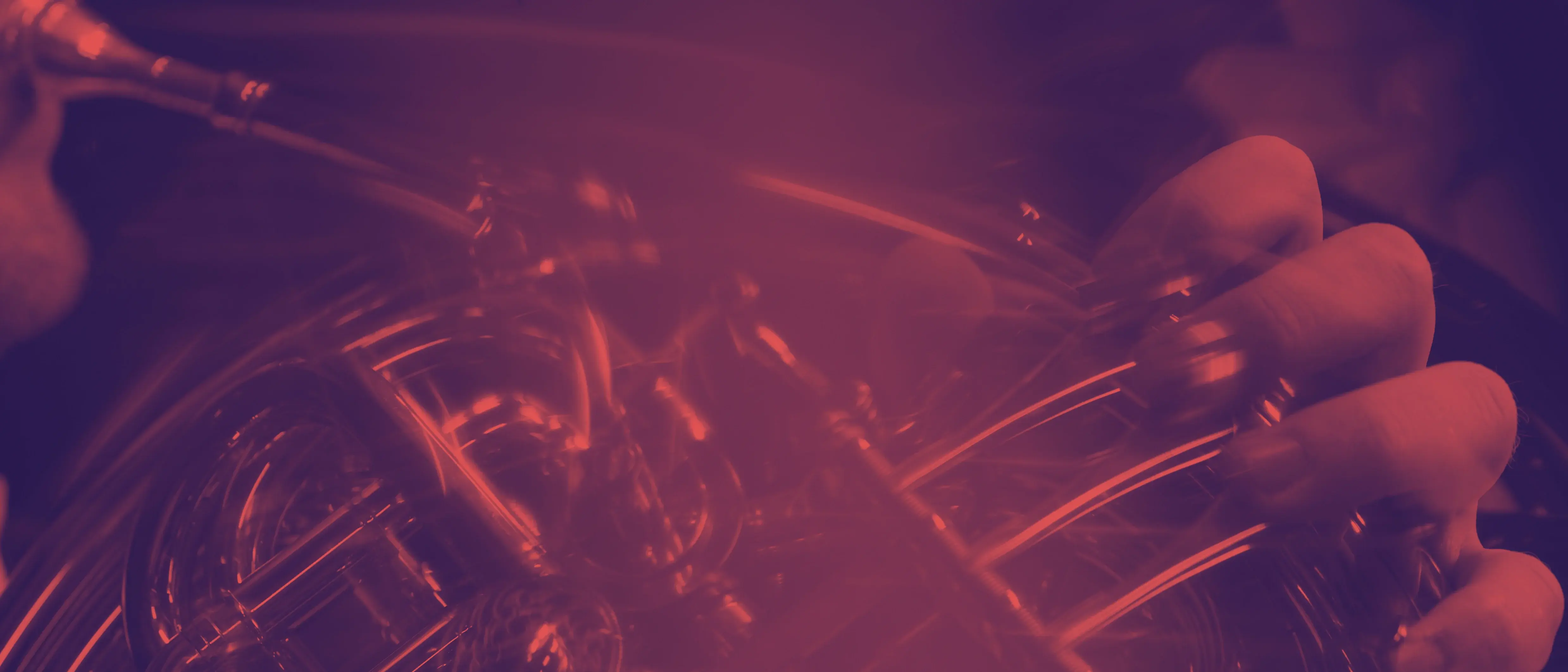 Nahaufnahme auf ein Horn, welches gespielt wird. Das Bild ist mit einem rötlich-dunkelvioletten Duoton-Filter eingefärbt.