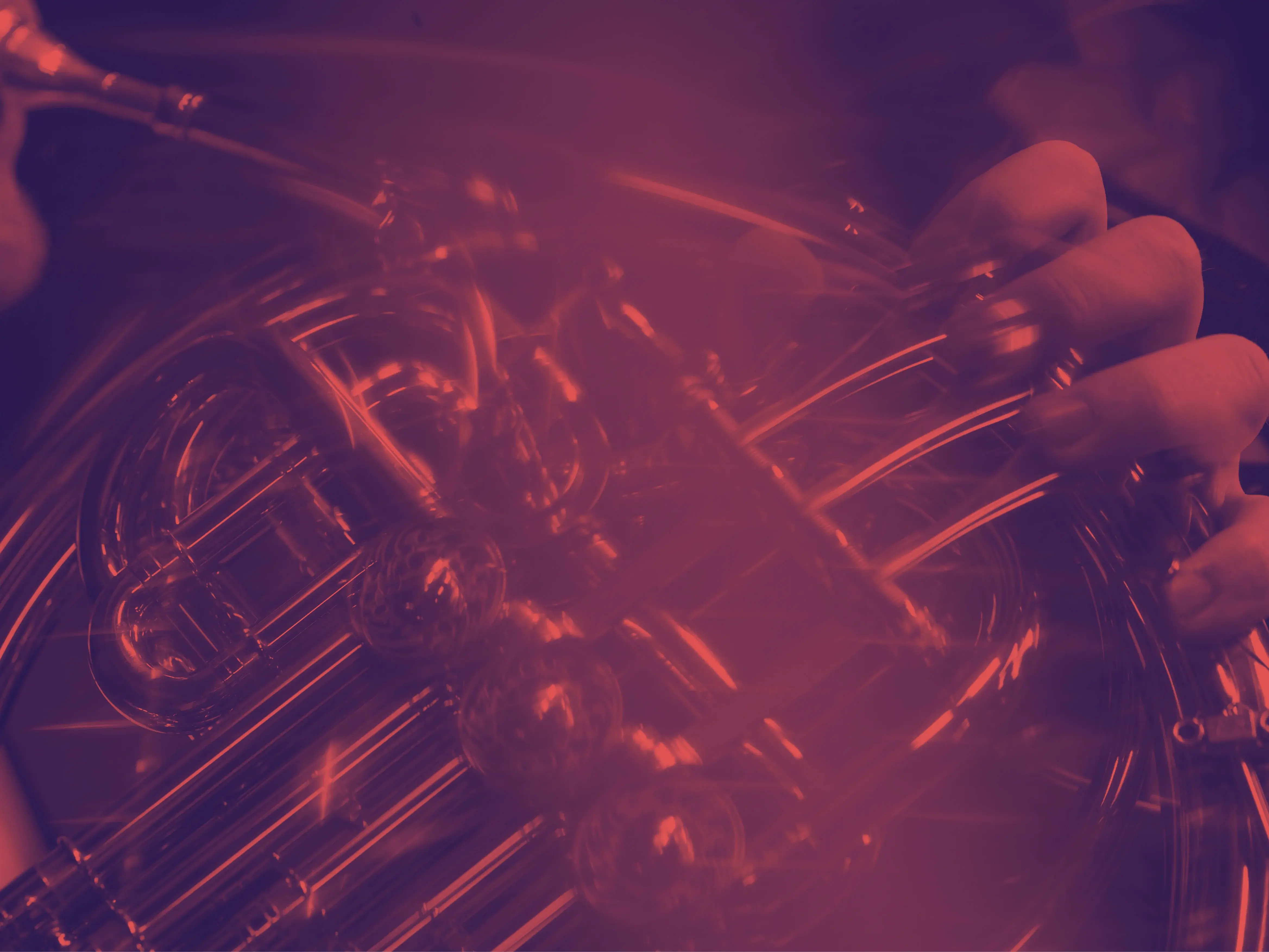 Nahaufnahme auf ein Horn, welches gespielt wird. Das Bild ist mit einem rötlich-dunkelvioletten Duoton-Filter eingefärbt.